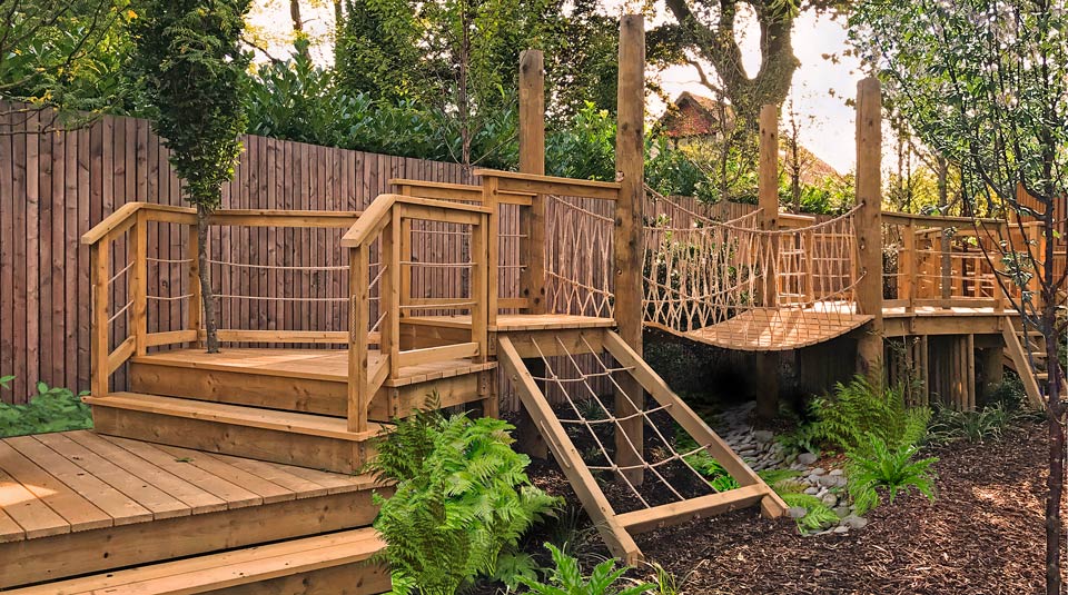 Elevated walkway & rope bridge leads to a contemporary treehouse